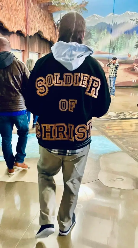 Apostello Archegos wearing a “Soldier of Christ” jacket walking forward in public, representing bold Christian faith, discipleship, and living unashamed for Jesus.